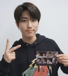 a young man holding up an album with his fingers in the air and pointing to it