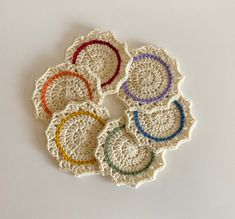 six crocheted coasters are arranged on a white surface