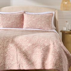 a bed with pink comforter and pillows on it