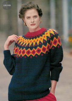 a woman wearing a sweater and red pants is walking down the street with her hand on her hip