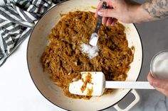 a person mixing food in a pan with a spatula next to a glass of milk