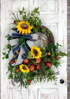 a wreath with sunflowers and apples is hanging on a door