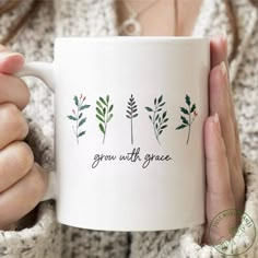 a woman holding a white coffee mug with green leaves on it and the words grow with grace