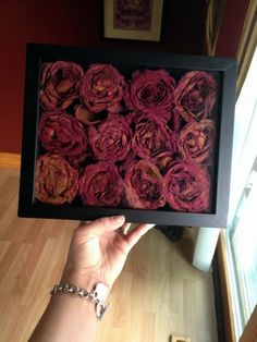 a person holding up a box filled with pink flowers