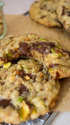 chocolate chip cookies with pistachios and nuts are on a cookie sheet next to a jar of dried pistachios