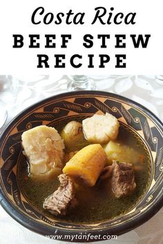 a bowl filled with beef stew and potatoes on top of a white cloth covered table