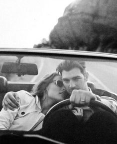 a man and woman sitting in a car kissing