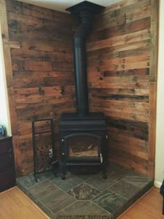 a wood burning stove in a room with wooden walls and floor boards on the wall