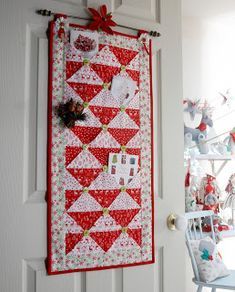 a red and white quilt hanging on the wall next to a chair with a christmas decoration