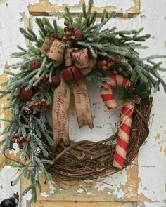 a christmas wreath hanging on the side of a door with candy canes and pine cones