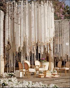 an outdoor wedding setup with chairs and chandelier hanging from the ceiling, surrounded by white flowers