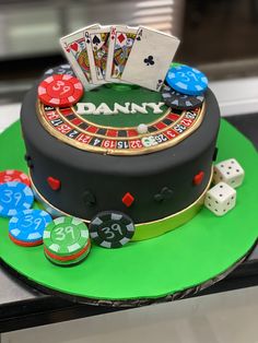 a casino themed cake with playing cards and dices on the top, sitting on a green platter