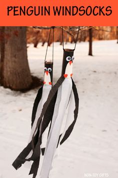 penguin wind socks hanging from a tree in the snow with text overlay that reads, how to make paper penguin windsocks