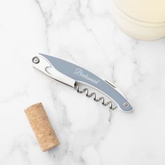 a bottle opener sitting on top of a marble counter next to a corkscrew