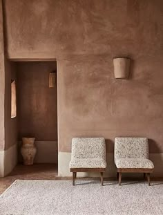 two chairs sitting next to each other in front of a wall with vases on it