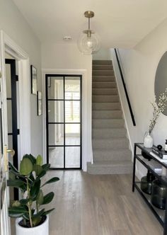 an entry way with stairs, mirror and vases on the side table in front of it