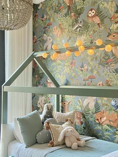 a child's bed with stuffed animals on the bottom and wallpaper behind it