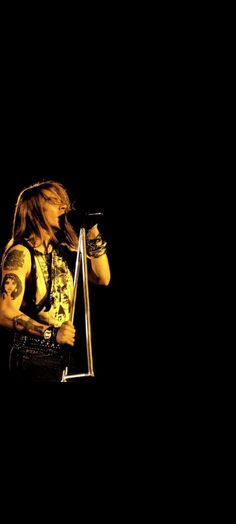 a man with long hair holding a microphone in his right hand and standing on stage