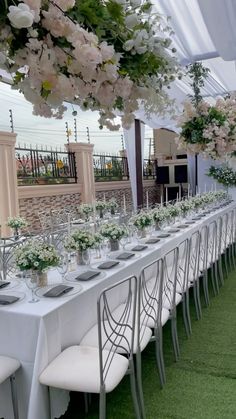 a long table is set up with white flowers and greenery for an outdoor event