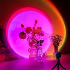 a vase filled with flowers sitting on top of a table next to a neon ball