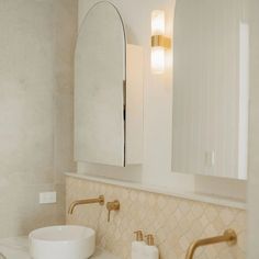 a white sink sitting under a bathroom mirror next to a wall mounted faucet