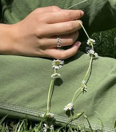 a person with their hand on some daisies