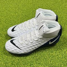 a pair of white and blue nike shoes on green grass with the soles off