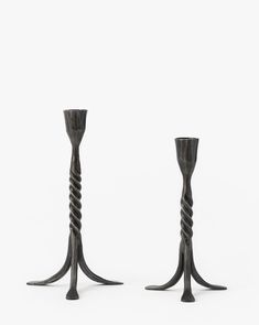 two tall metal candlesticks with twisted stems on each side, against a white background