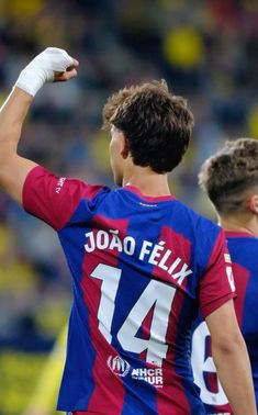 two soccer players standing next to each other with their arms in the air and one holding his fist up