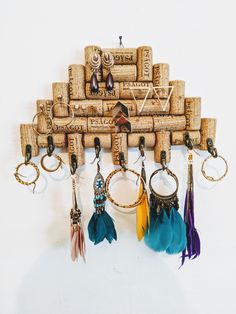 several different colored feathers hang from corks on a wall mounted wine bottle holder with key chains