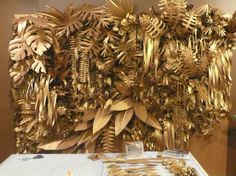 there is a gold sculpture made out of leaves and branches on the side of a table