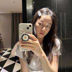 a woman taking a selfie in front of a mirror with a flower on it