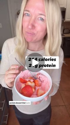 a woman holding a bowl of ice cream with strawberries in it and two calories 2 g protein