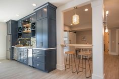 an open kitchen and dining room area with bar stools in the center, cabinets on both sides