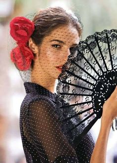 a woman with a red flower in her hair holding a black and white parasol