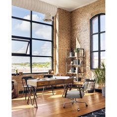 an office with large windows and wooden flooring in front of a brick wall, overlooking the city