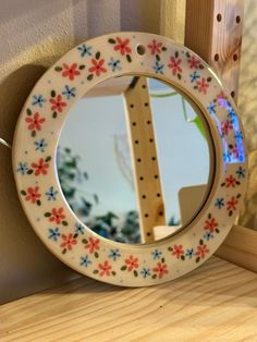 a round mirror sitting on top of a wooden shelf