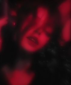 a blurry image of a woman's face with red light coming from her mouth