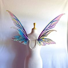 a mannequin with colorful wings on it's head and neck, standing in front of a white wall