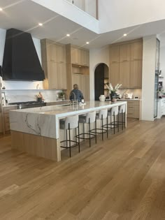 a large kitchen with wooden floors and white counter tops on one side, an island in the other