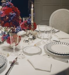 the table is set with plates, silverware and flowers in vases on it