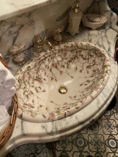 a white sink sitting next to a basket on top of a marble countertop in a bathroom