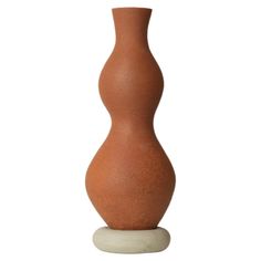 a brown vase sitting on top of a white base