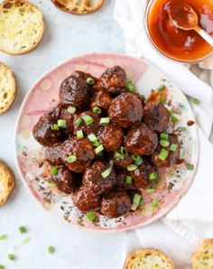 meatballs on a plate next to bread and dipping sauces in a glass bowl