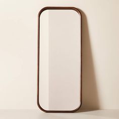 a mirror on the wall next to a white wall with a wooden frame in it