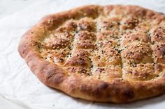 a freshly baked pizza sitting on top of a piece of wax paper with black pepper sprinkles