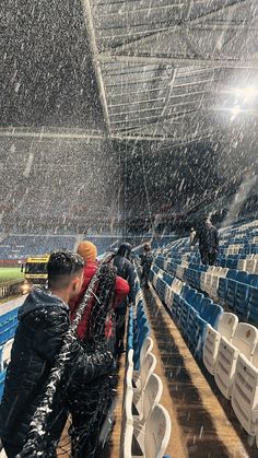 a man standing in the rain at a stadium with his arm wrapped around another person's shoulder