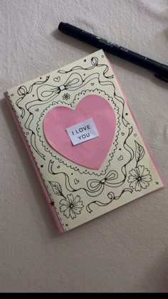 a notepad with a pink heart and i love you written on it next to a pen