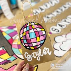 a person holding up a brown bag with an ornament on it that says gaylor