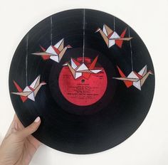 a record with origami cranes hanging from it's side on a wall